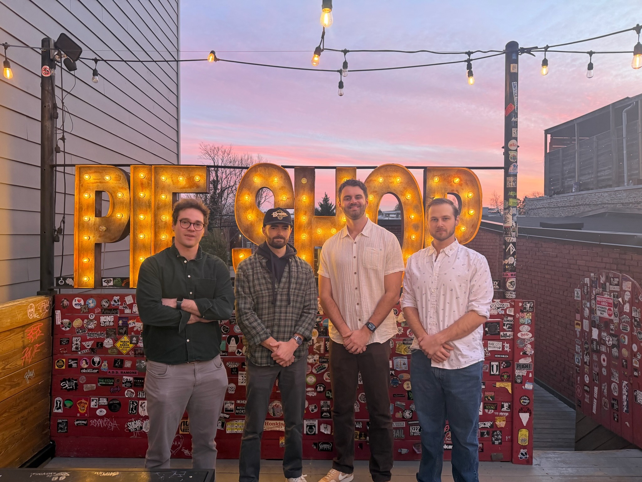 All four members of Wheat for Sheep together in front of the Pie Shop sign